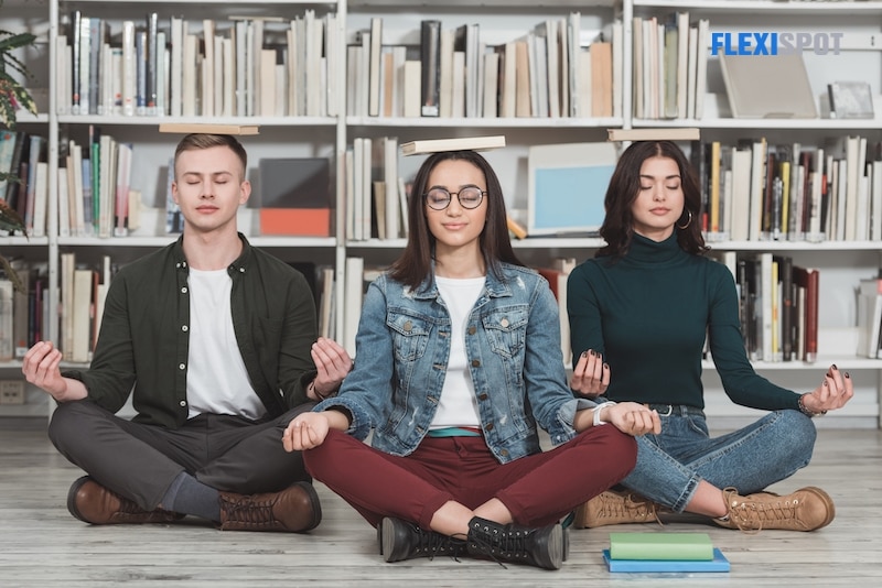 Multicultural students meditate with books in the library