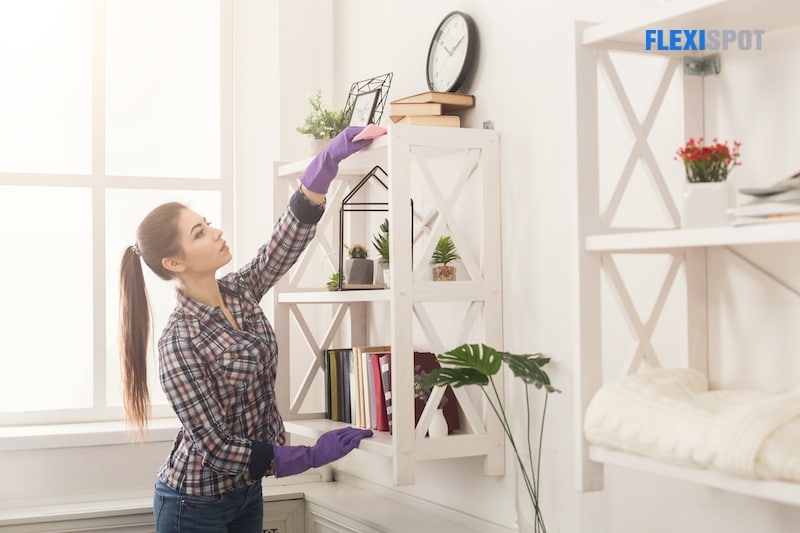 Woman cleaning dust from bookshelf