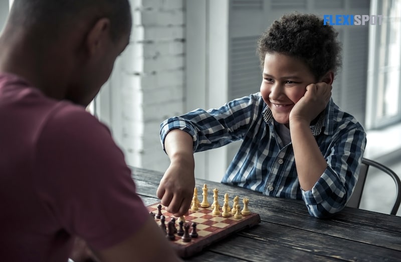 Short shot of father and young son playing chess at home