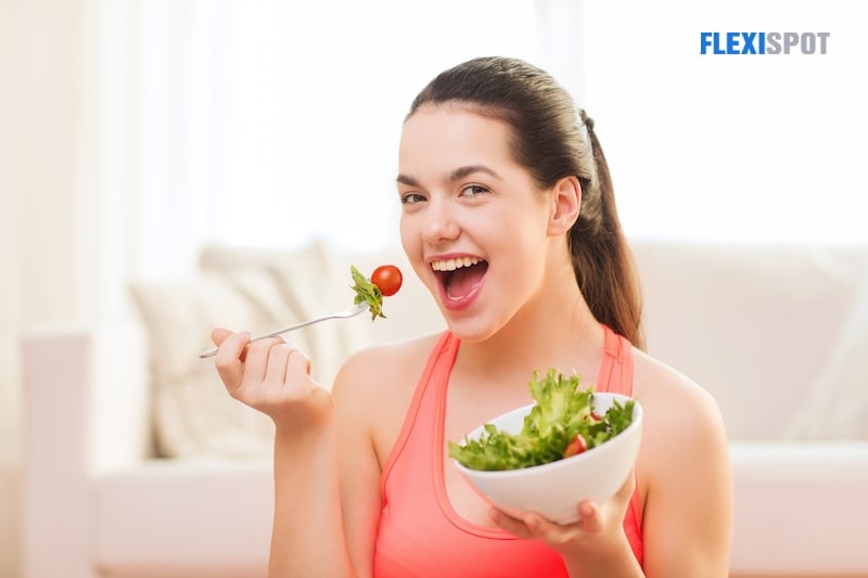 Smiling teenage girl with green salad at home