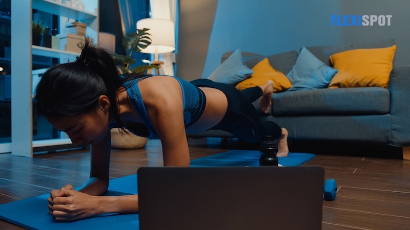 Young Asia lady in sportswear exercises doing work out and using laptop to watch yoga video tutorial at home night. Distant training with personal trainer, social distance, online education concept.